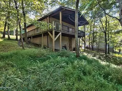 a house on a hill with trees and grass at Clubhouse Lakeview Chalet in East Stroudsburg