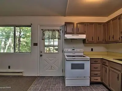 a kitchen with a white stove top oven next to a door at Clubhouse Lakeview Chalet in East Stroudsburg