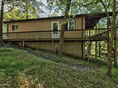 a house with a deck in the woods at Clubhouse Lakeview Chalet in East Stroudsburg
