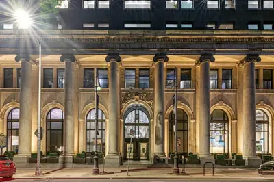 a large building with columns on a city street at The Ledger Residences by Sosuite - Old City in Philadelphia