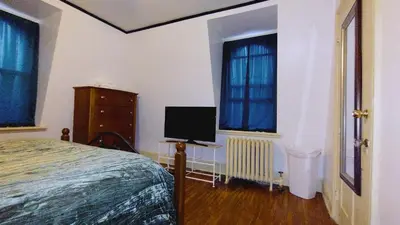 a bedroom with a bed and a tv in it at Mini Mansion Hotel near public transportation is the yellow and green house on the corner of 8th st and Madison avenue in Plainfield