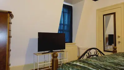a television sitting on a stand in a bedroom at Mini Mansion Hotel near public transportation is the yellow and green house on the corner of 8th st and Madison avenue in Plainfield