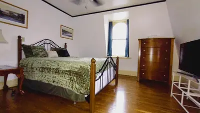 a bedroom with a bed and a dresser and a window at Mini Mansion Hotel near public transportation is the yellow and green house on the corner of 8th st and Madison avenue in Plainfield