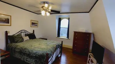 a bedroom with a bed and a dresser and a window at Mini Mansion Hotel near public transportation is the yellow and green house on the corner of 8th st and Madison avenue in Plainfield