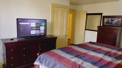 a bedroom with a bed and a television on a dresser at Mini Mansion Hotel near public transportation is the yellow and green house on the corner of 8th st and Madison avenue in Plainfield