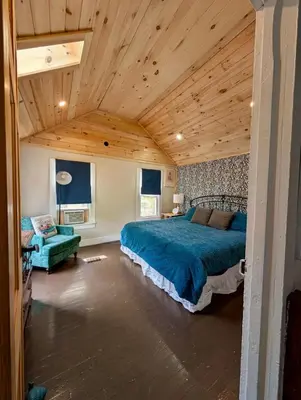 a bedroom with a large bed and a wooden ceiling at Charming 120-year-old farmhouse by the creek. in Starlight