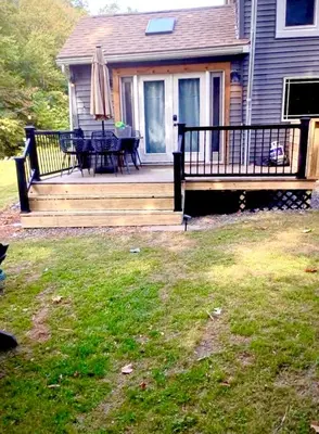 a deck with a table and an umbrella on a house at Charming 120-year-old farmhouse by the creek. in Starlight