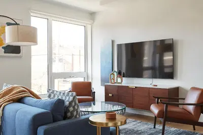 a living room with a blue couch and a tv at Harmony Lofts on Jackson 2 in Hoboken
