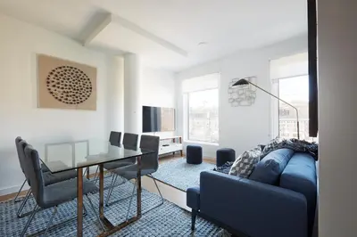 a living room with a blue couch and a glass table at Harmony Lofts on Jackson 2 in Hoboken