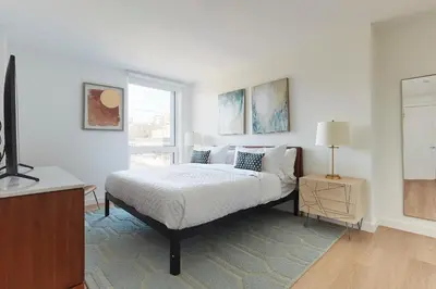 a white bedroom with a bed and a window at Harmony Lofts on Jackson 2 in Hoboken