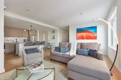 a living room with a couch and chairs and a kitchen at Harmony Lofts on Jackson 2 in Hoboken