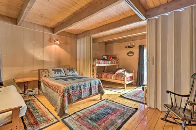 a bedroom with a bed in a room with rugs at Fire Pit and Grill Lakefront Poconos Cottage! in East Stroudsburg