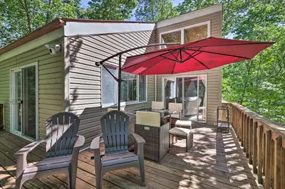 a patio with a red umbrella on a deck at Fire Pit and Grill Lakefront Poconos Cottage! in East Stroudsburg