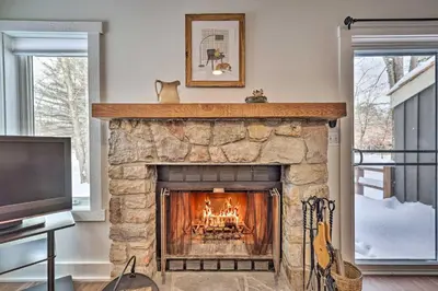 a living room with a stone fireplace and a tv at Less Than 1 Mi to Jack Frost Lake Harmony Townhome! in Lake Harmony