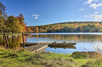 a boat is docked at a dock on a lake at Near Skiing Pocono Lake Cabin with Screened Patio in Pocono Lake