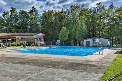 a swimming pool at a park with a building and trees at Large Deck and Resort Amenities Lake Ariel Retreat in Lake Ariel