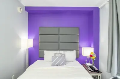 a purple bedroom with a white bed and two lamps at Canal Loft Hotel in New York