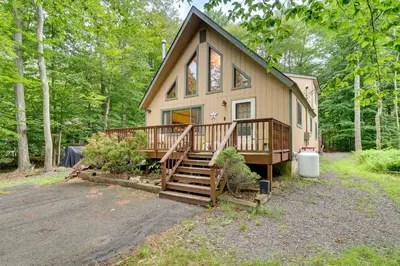 a house with a porch and a staircase in the woods at Lake Access and Decks Pet-Friendly Poconos Cabin! in Pocono Lake