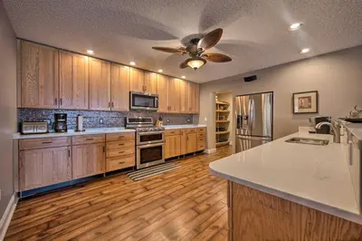 a large kitchen with wooden cabinets and a ceiling fan at Dock and Hot Tub Susquehanna River Retreat! in Pequea