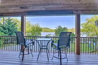 a porch with two chairs and a table with a view of a lake at Dock and Hot Tub Susquehanna River Retreat! in Pequea
