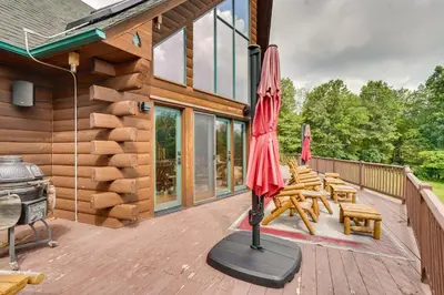a patio with an umbrella and chairs and a grill at Luxury Log Cabin with EV Charger and Mtn Views! in Blairstown