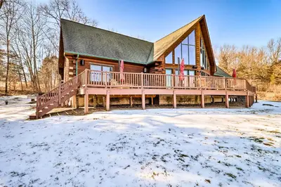 a log cabin with a large deck in the snow at Luxury Log Cabin with EV Charger and Mtn Views! in Blairstown