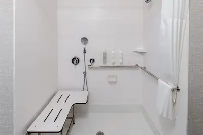 a white bathroom with a bench and a shower at Hampton Inn Monticello, Ny in Monticello