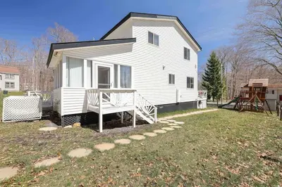 a white house with a porch on a yard at Cozy Poconos Mountain House with 3 bedrooms in Tobyhanna