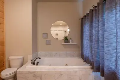 a bathroom with a tub and a toilet and a mirror at The Mountain Lodge in Elliottsburg