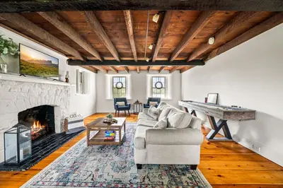 a living room with a couch and a fireplace at Downingtown Manor - 1900s Farmhouse with Creek Views in Downingtown