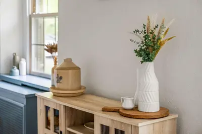 a table with a vase with flowers on it at Downingtown Manor - 1900s Farmhouse with Creek Views in Downingtown