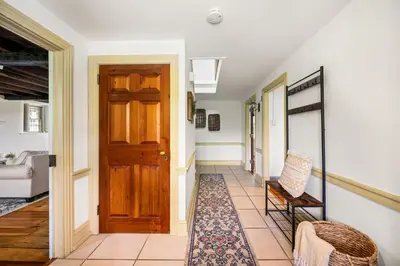 a hallway with a wooden door and a chair at Downingtown Manor - 1900s Farmhouse with Creek Views in Downingtown