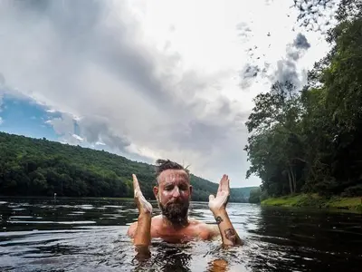 a man in a river with his hands in the water at Slumberland at the River's Edge in Pond Eddy