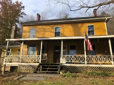 an old house with an american flag on the porch at Slumberland at the River's Edge in Pond Eddy