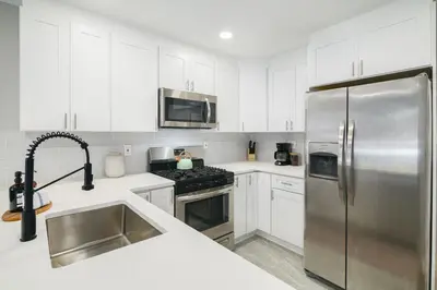 a kitchen with white cabinets and a stainless steel refrigerator at 2BR in Heart of Queen Village - walk to everything! in Philadelphia