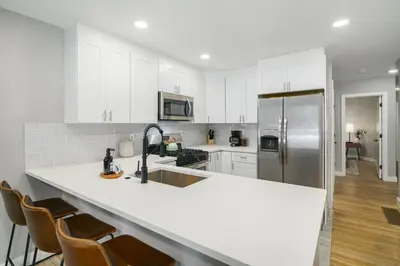 a kitchen with white cabinets and a stainless steel refrigerator at 2BR in Heart of Queen Village - walk to everything! in Philadelphia