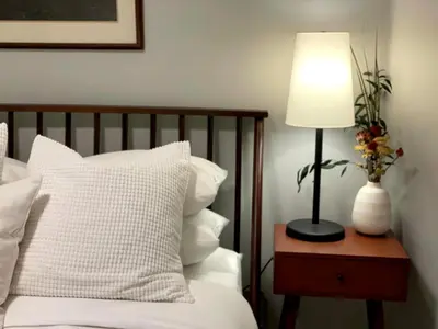 a lamp on a table next to a bed with white pillows at 2BR in Heart of Queen Village - walk to everything! in Philadelphia