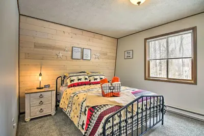a bedroom with a bed and a wooden wall at Tobyhanna Cabin with Deck, Community Pool and Golf! in Tobyhanna