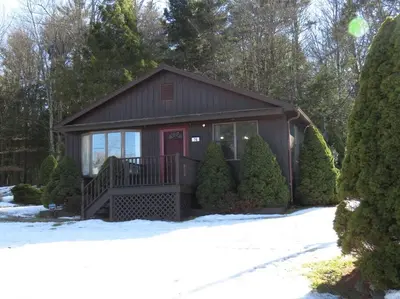 a small house with a porch in the snow at Catskills Cottage with Lake View Book Now in Rock Hill