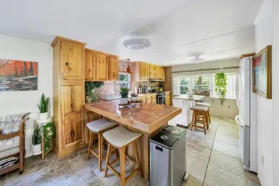 a kitchen with wooden cabinets and a large island with bar stools at 2 Lake Cabins Poolhottub Game Room & Courts in Highland Lake