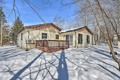 a house with a deck in the snow at 1 Mi to Lake Family-Friendly Tobyhanna Home in Tobyhanna