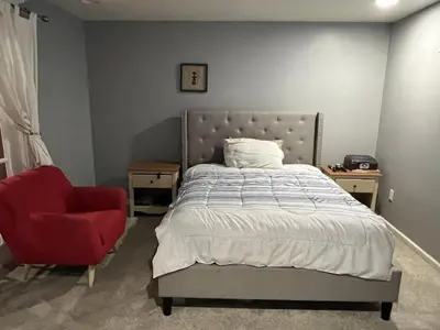 a bedroom with a bed and a red chair at 5BRwithBand&Piano setup Private Gym Theater&Entry at Cherry Hill in Cherry Hill