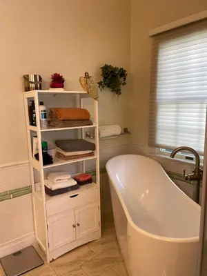 a bathroom with a bath tub and a shelf with towels at 5BRwithBand&Piano setup Private Gym Theater&Entry at Cherry Hill in Cherry Hill
