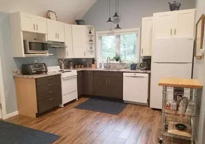 a kitchen with wooden floors and white cabinets at Cottage at Millpond Falls - A Romantic Escape in Warwick