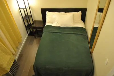 a bed in a small room with a mirror at MOTELCASA Guest House Newark NJ in Newark