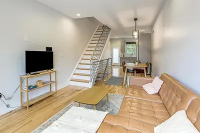 a living room with a couch and a staircase at 3-Story Philly Townhouse 2 Mi to University City! in Philadelphia