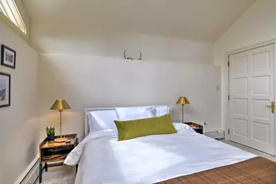 a bedroom with a white bed with a green pillow on it at Catskill Getaway on 6 Acres with Swimming Pond! in Liberty