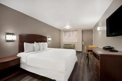a hotel room with a large white bed and a desk at Red Carpet inn Edison in Edison