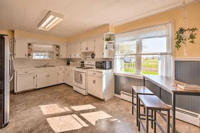 a kitchen with white cabinets and a table and a window at Quiet Elizabethville Home with Fire Pit and Views in Elizabethville