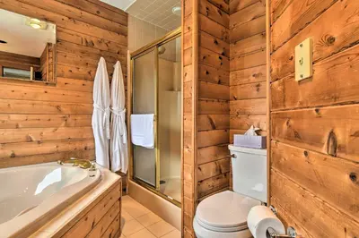 a bathroom with a toilet and a tub and wooden walls at Decked-Out Home Hot Tub, Pool, Fire Pit and More! in Monroe